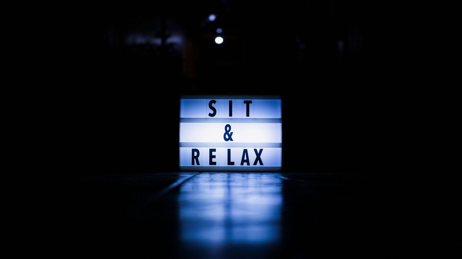 A glowing lightbox with 'Sit & Relax' text against a dark background, perfect for calming themes.
